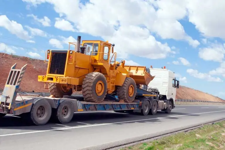 A flatbed trailer moving construction vehicle.